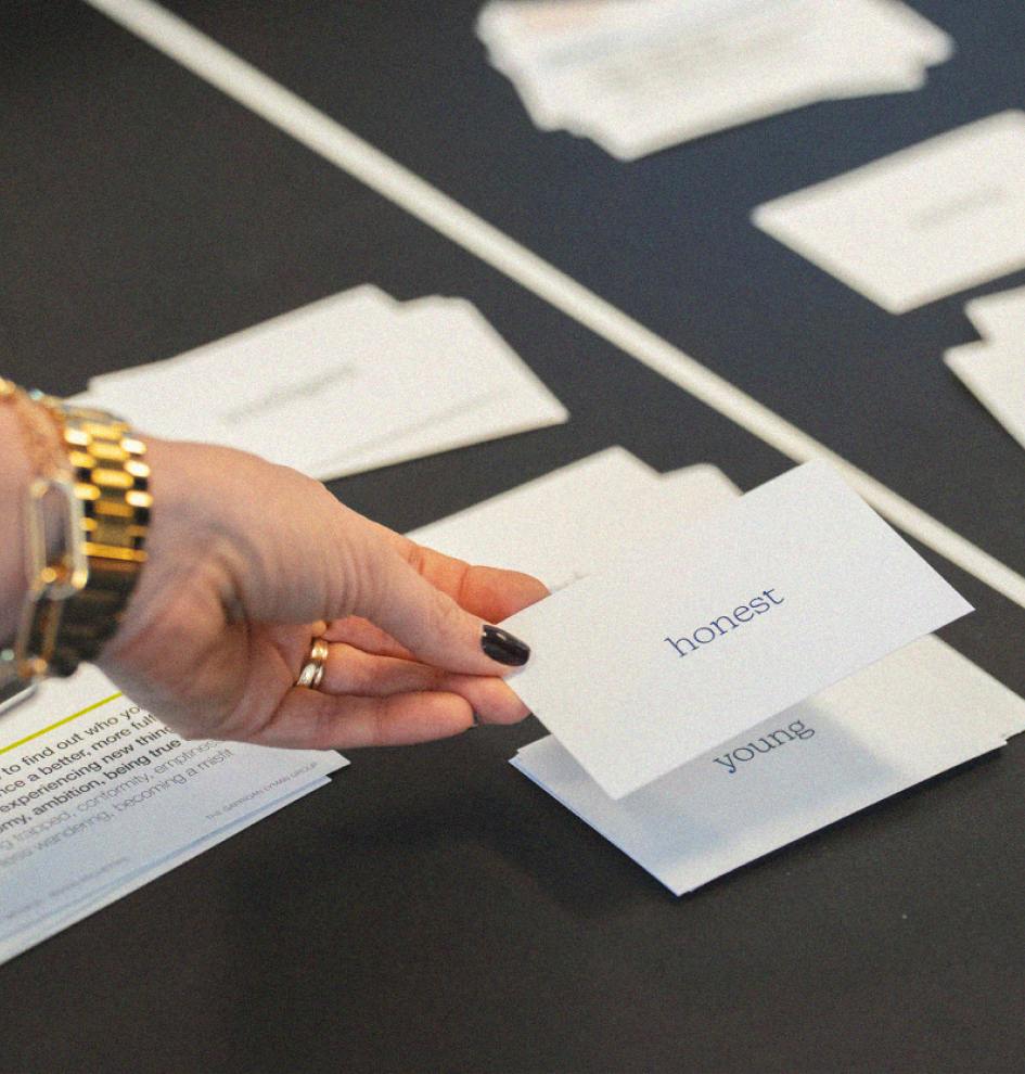 Close-up of a hand choosing between cards with brand attributes including 'honest' and 'young.'