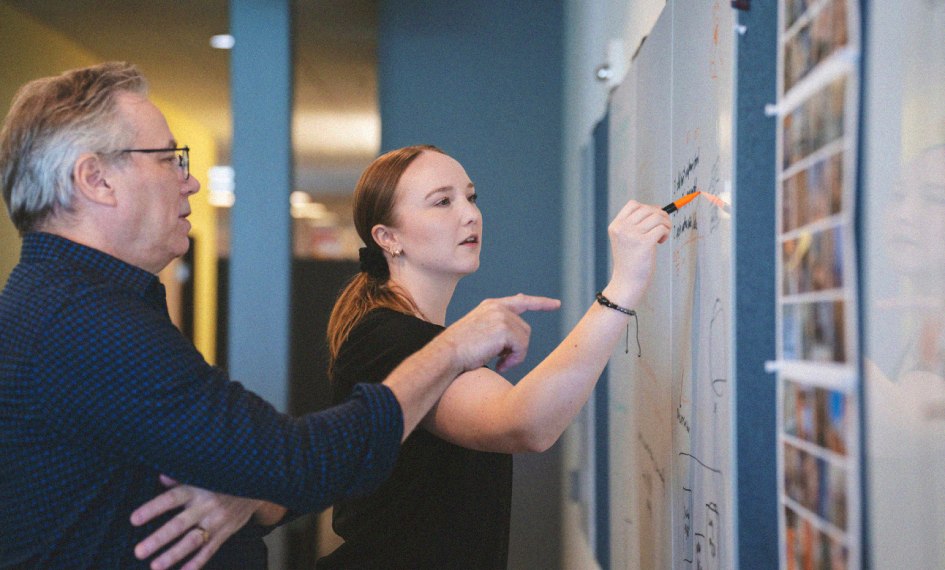 DCG ONE team members connect research with brainstorming on a whiteboard.