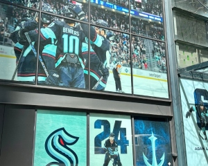 Large-format signage of the Seattle Kraken on a building emphasizes the team celebrating.